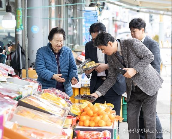 김돈곤 청양군수가 청양전통시장에서 과일을 고르며 농어촌 기본소득을 사용하는 모습