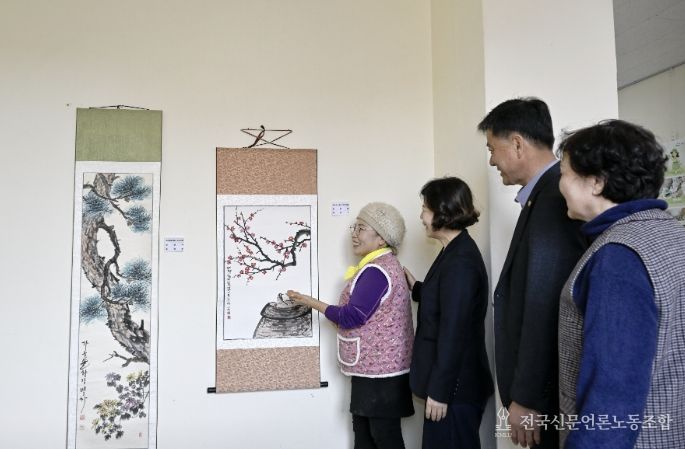 영인면 행정복지센터 층간 통로에 전시된 문인화반 작품을 주민들이 감상하고 있다.