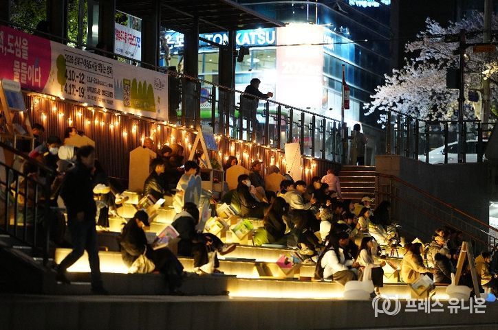 야간 조명이 켜진 성북천 수변활력거점에서 시 민들이 여유롭게 공연과 휴식을 즐기고 있다.